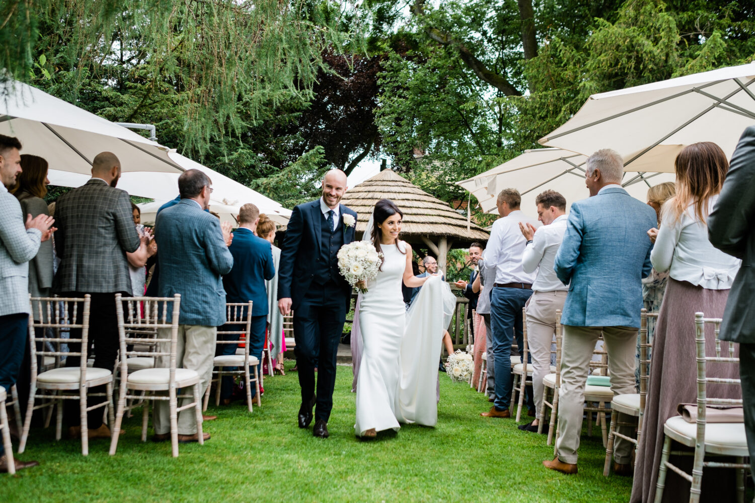 Bride and groom walk back down the aisle together at Eyam Hall outdoor wedding ceremony Bride and groom walk back down the aisle together at Eyam Hall outdoor wedding ceremony