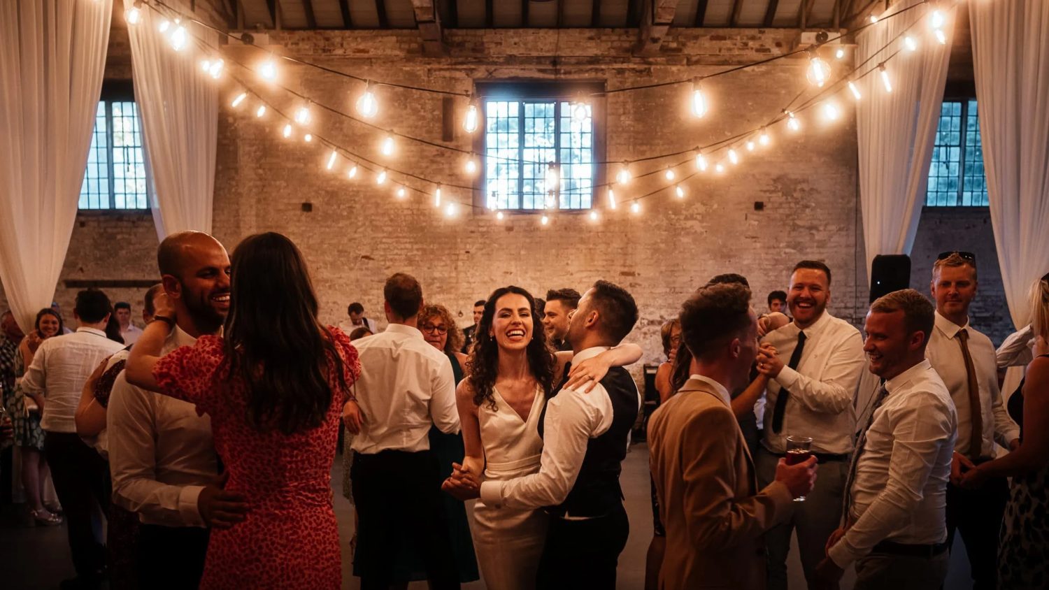 Bride and groom and wedding guests dance at Calke Abbey Riding School Bride and groom and wedding guests dance at Calke Abbey Riding School