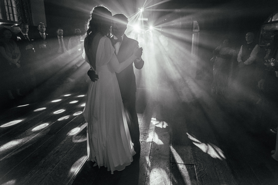 Documentary Wedding Photographer Nottingham - Simon Dewey Grainy black and white image of bride and groom on the dancefloor amongst streams of light. Atmospheric wedding dancefloor image. Documentary reportage wedding photojournalism.